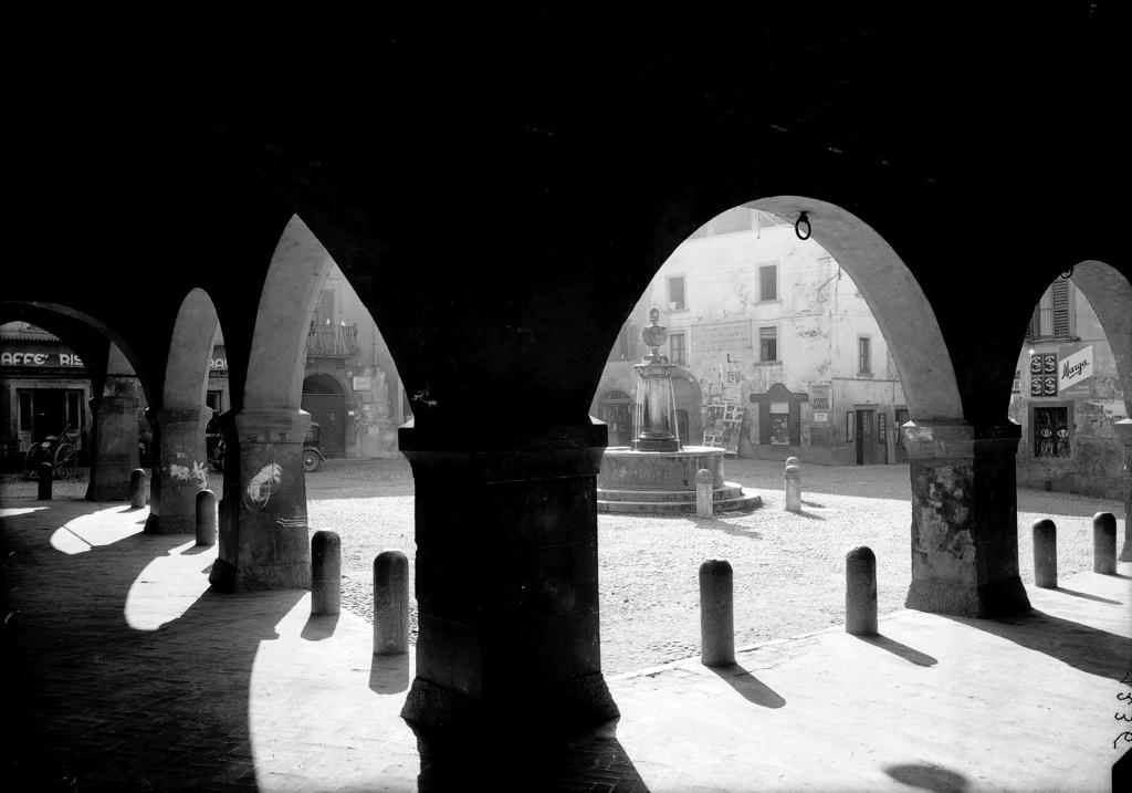 Piazza Con Fontana Vista Da Un Cortile Con Archi · Historify